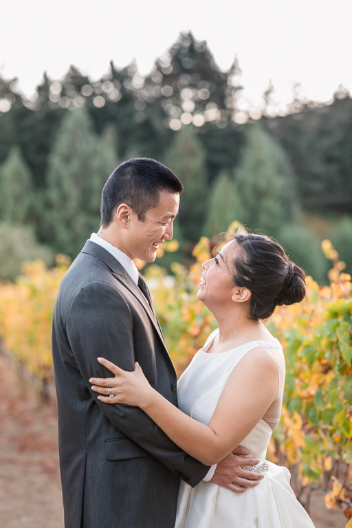 newlywed couple looking at each other lovingly in the vineyards