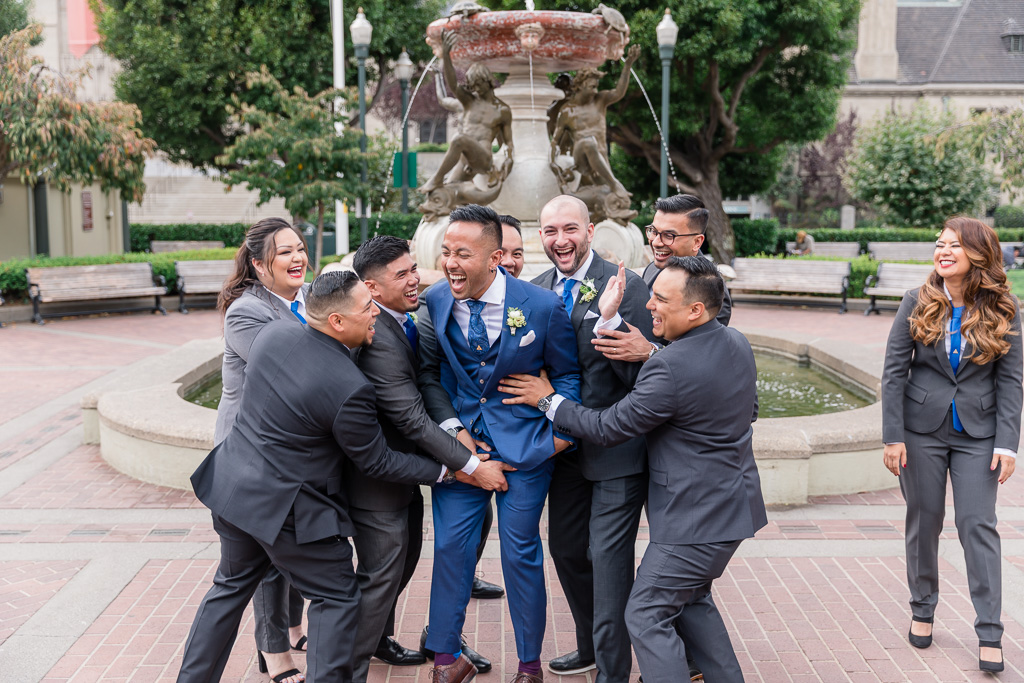 fun photo of groomsmen and groomswomen tackling the groom