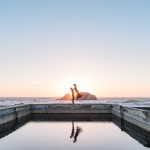 colorful sunset Sutro Baths photo with groom lifting bride up into the sky