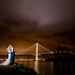 amazing wedding photo of bride and groom lit against the night sky in front of the Oakland Bay Bridge