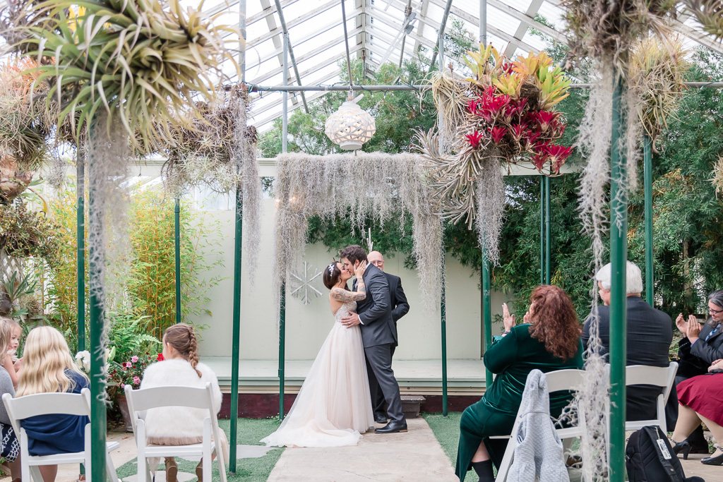 wedding ceremony first kiss inside a pretty greenhouse garden