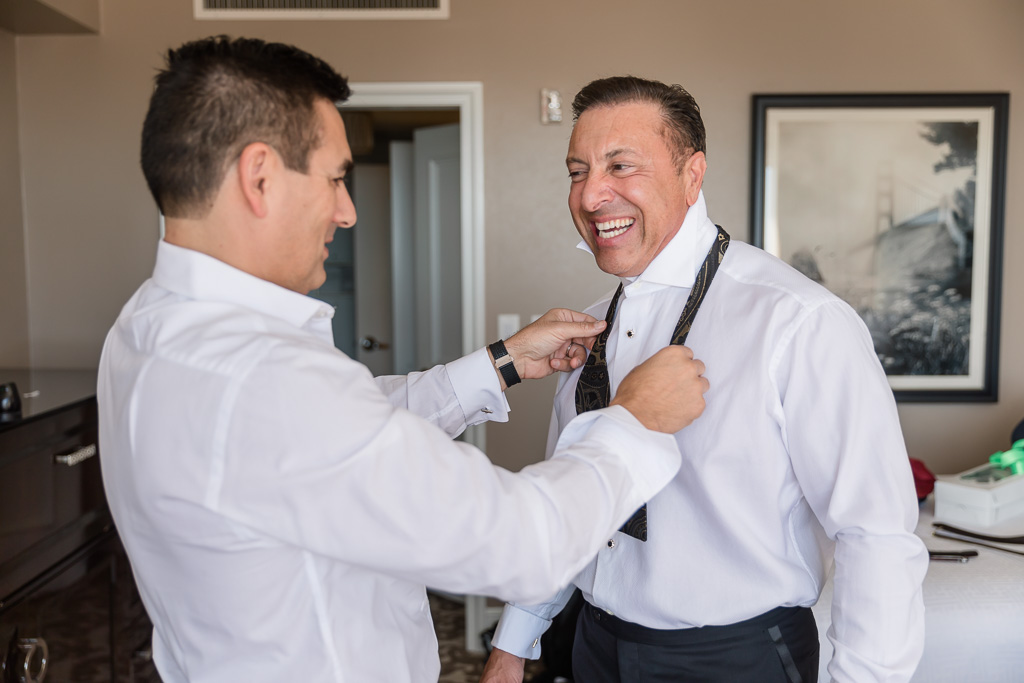 best man helping groom with his bow tie
