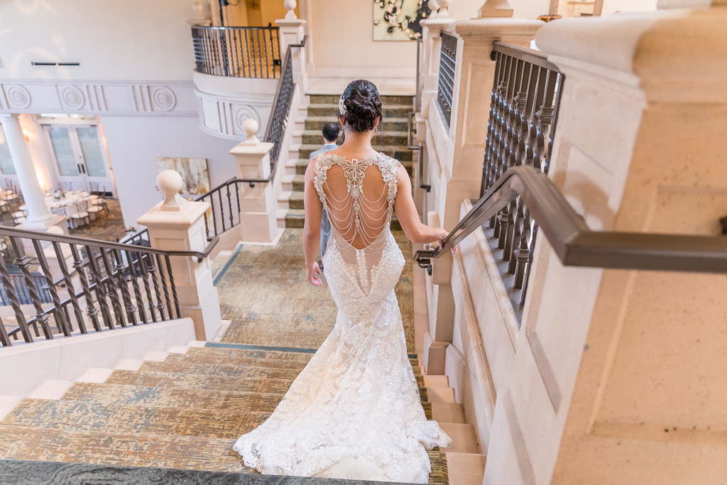 bride walking down the staircase for a first look with her groom