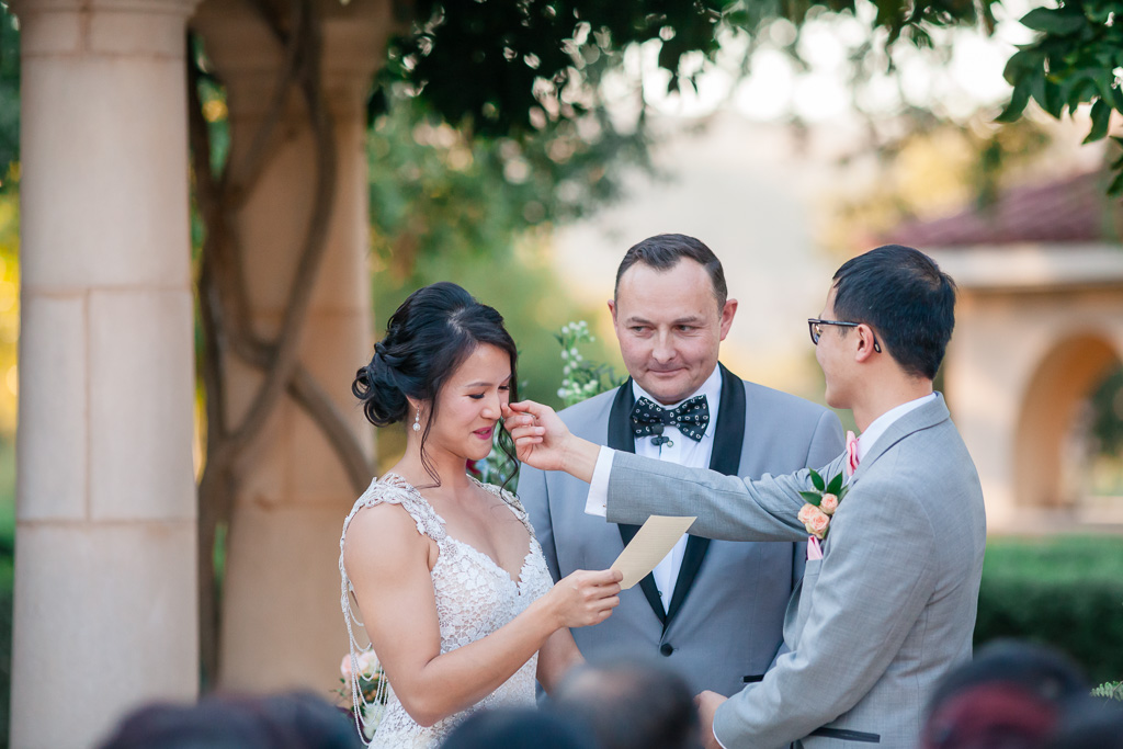 groom wiping away bride's tears during vow exchange