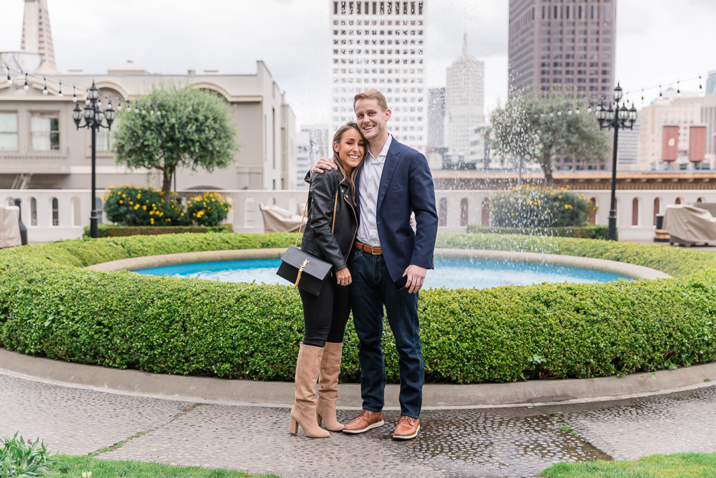 happy newly-engaged couple in front of Fairmont Hotel outdoor fountain