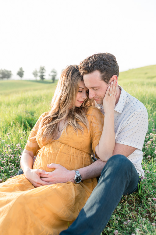 maternity photos sitting down in grassy field