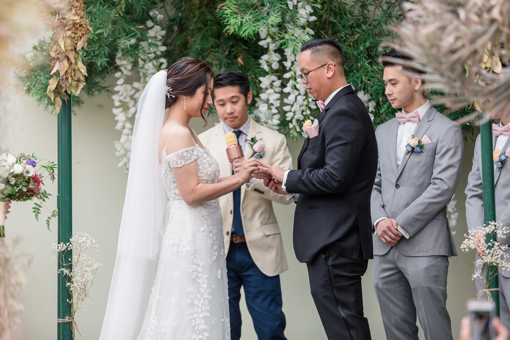 couple exchanging wedding rings in front of the orchids