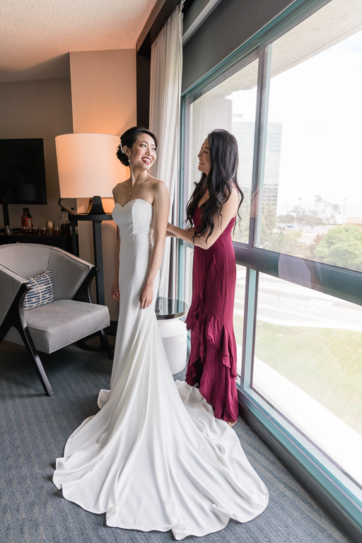 bride getting into her dress with the help of her sister