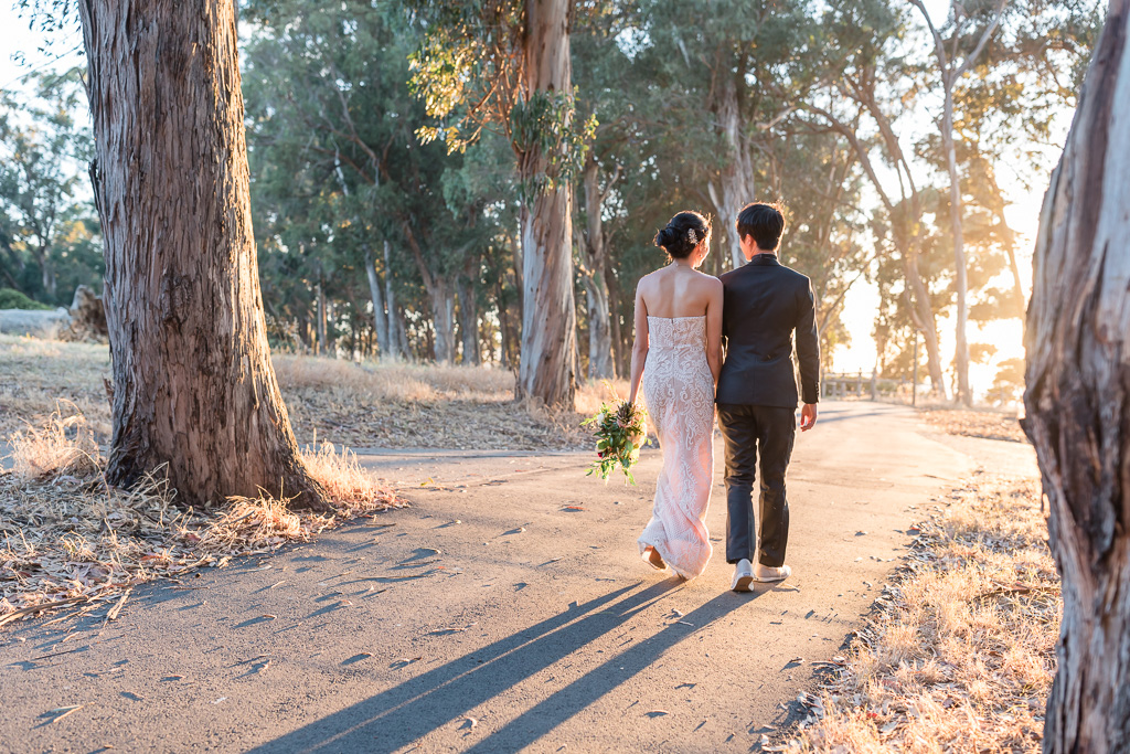 gorgeous sunlight pouring on bride and groom walking on Coyote Point trail