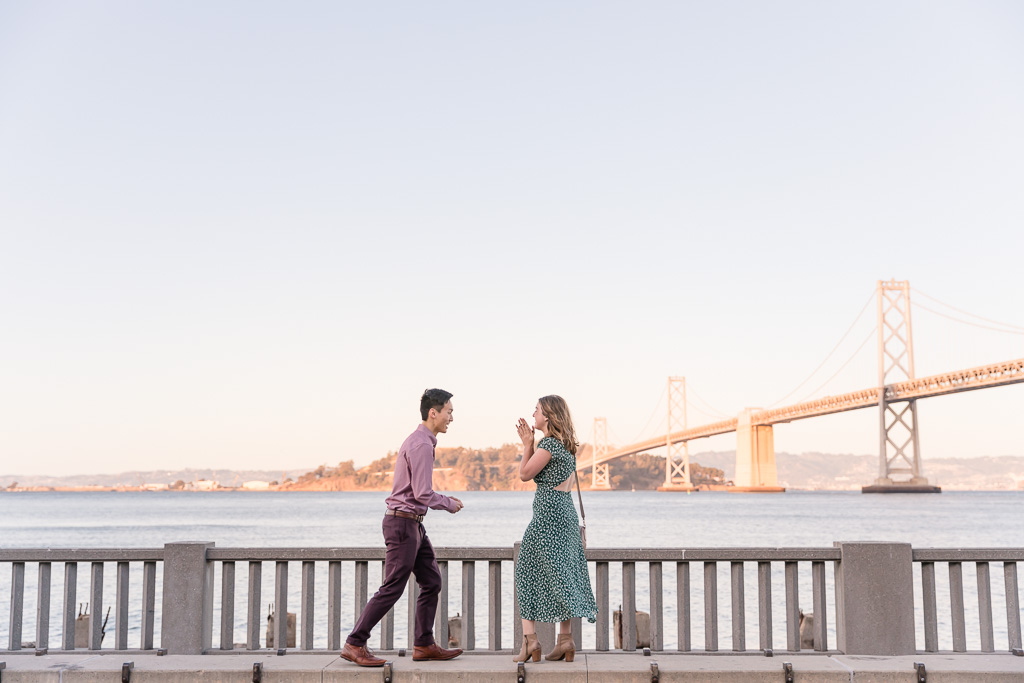 he is about to bend down on one knee and ask her to marry him in front of the bay bridge