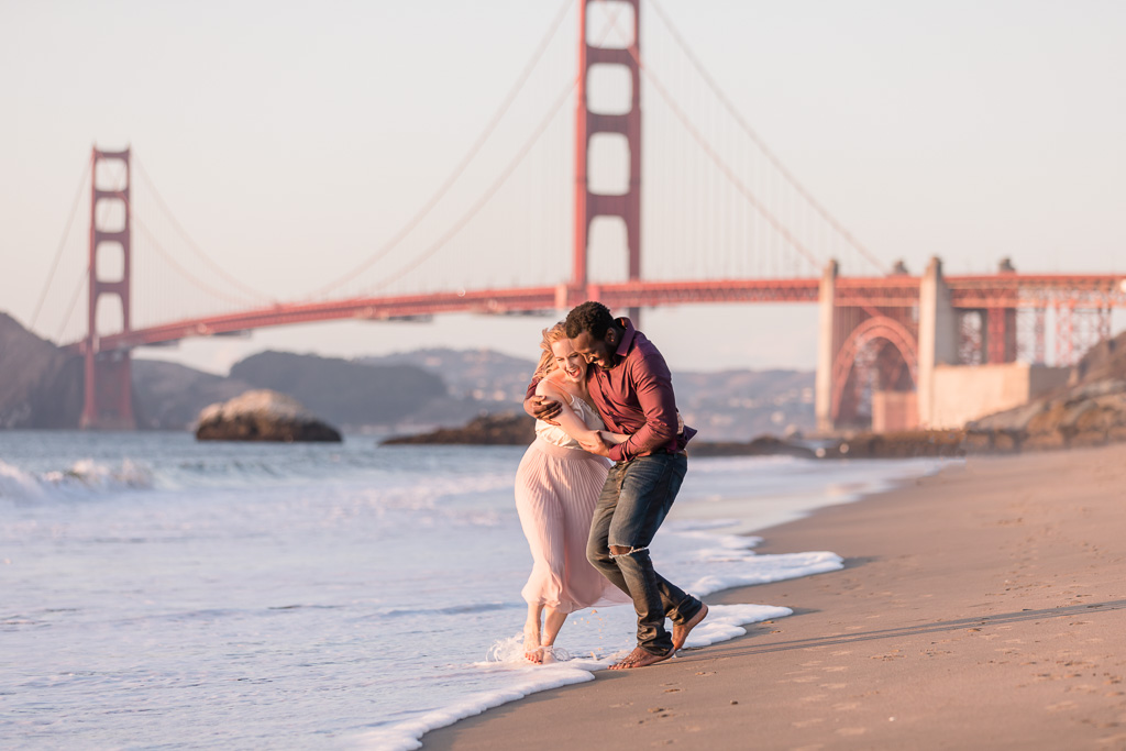 cute engagement pictures on Baker Beach playing in the water