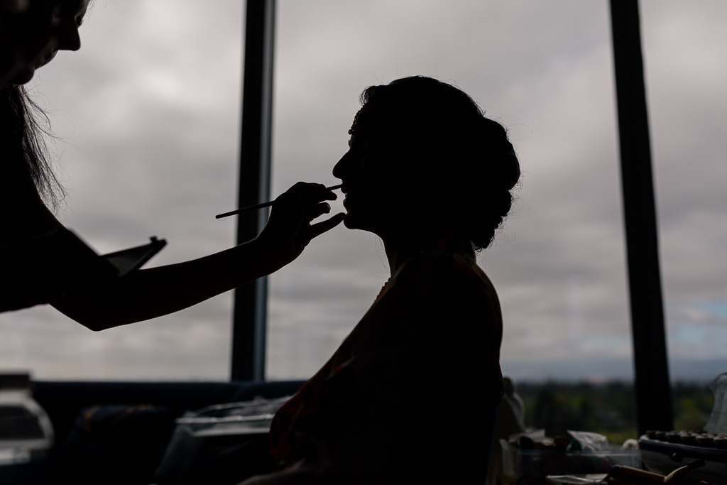 silhouette picture of the bride getting her makeup done