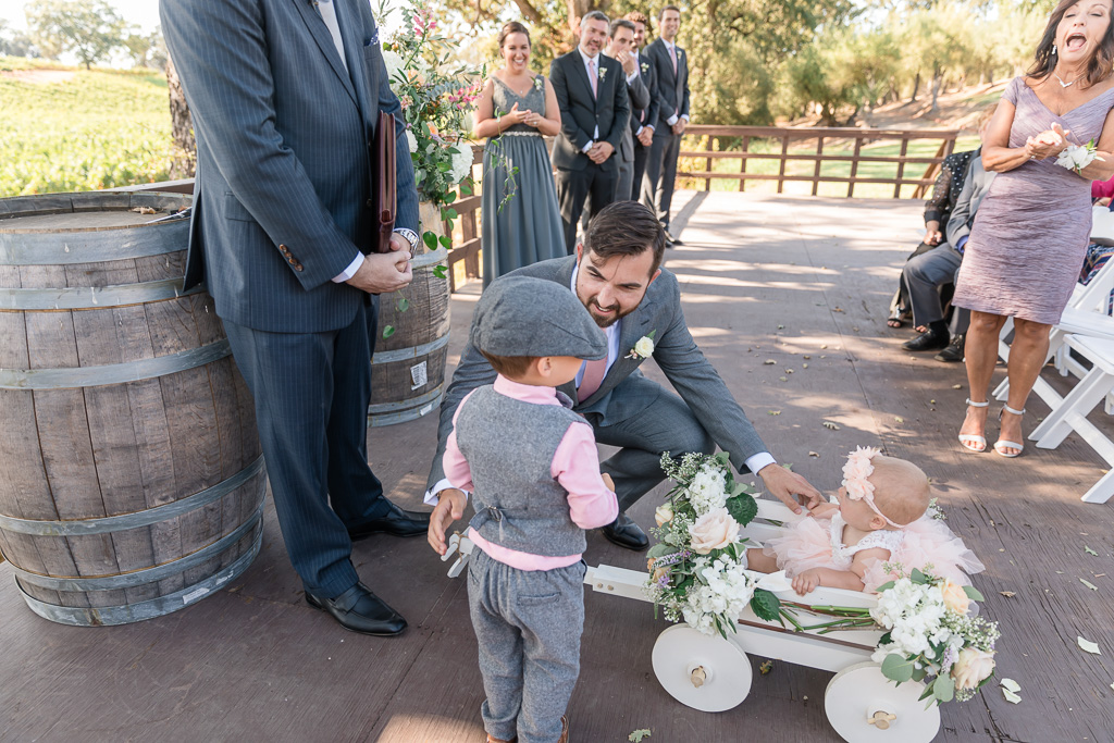 ring bearer pushes the cutest baby flower girl in a floral wagon