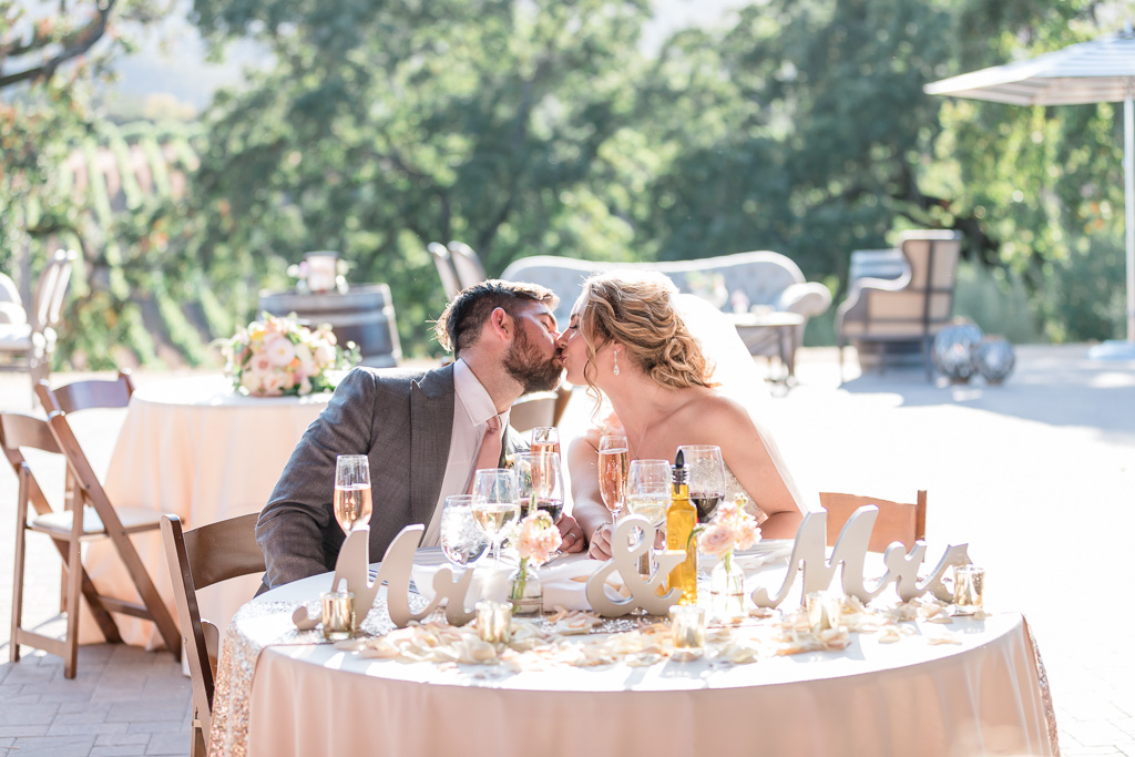 bride and groom kissing at sweetheart table