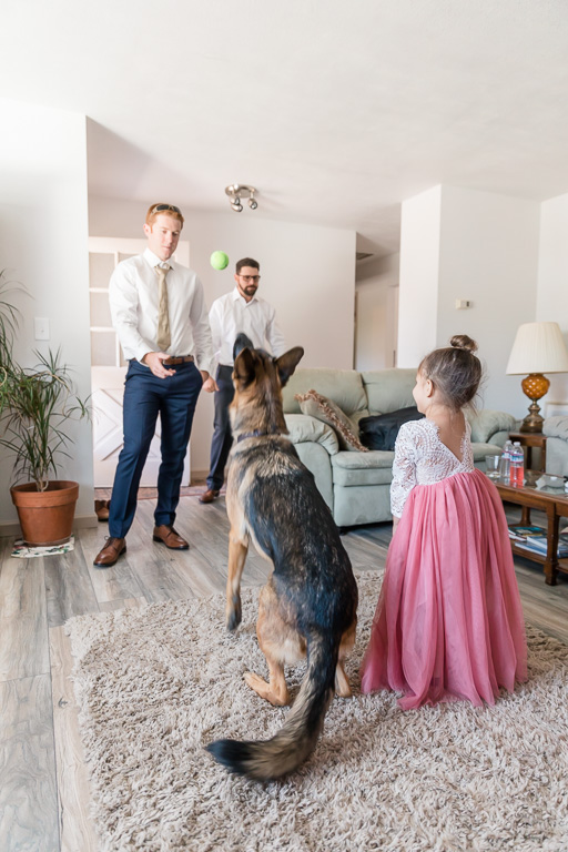 groom and flower girl playing fetch with the dog ring bearer