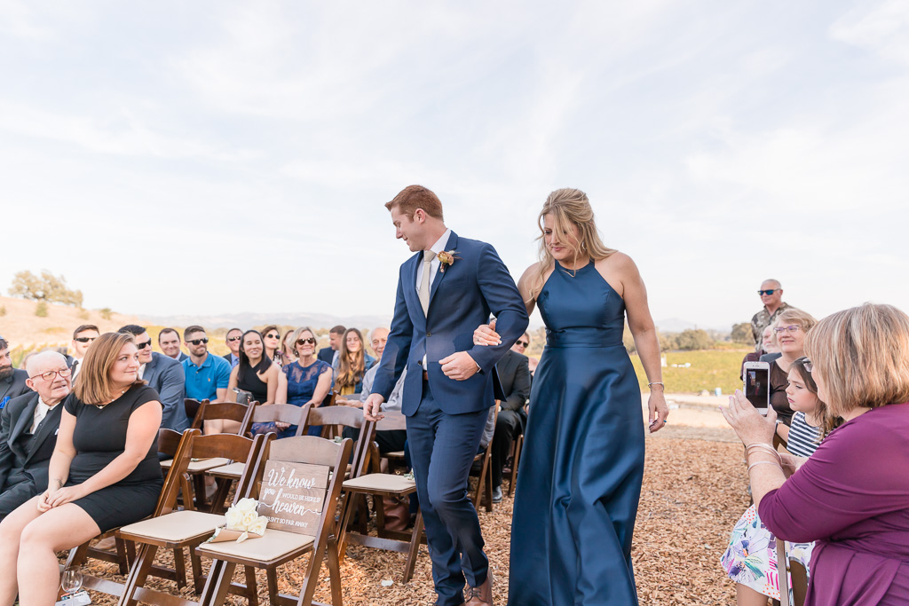 groom walking down the aisle with his mother
