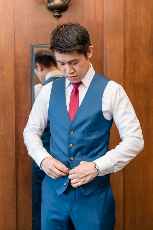 groom buttoning his vest