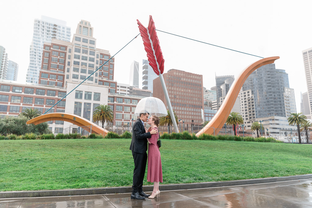 cute engagement photo in the rain with clear umbrella at Cupid’s Span