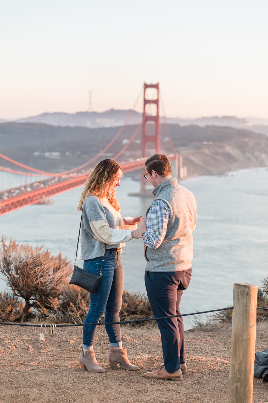 putting on engagement ring at the Golden Gate Bridge