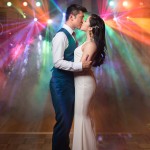creative wedding reception photo with brightly colored DJ lights in the background lighting up fog