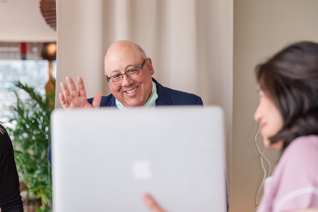 father of the bride waving at the bridesmaids on computer screen
