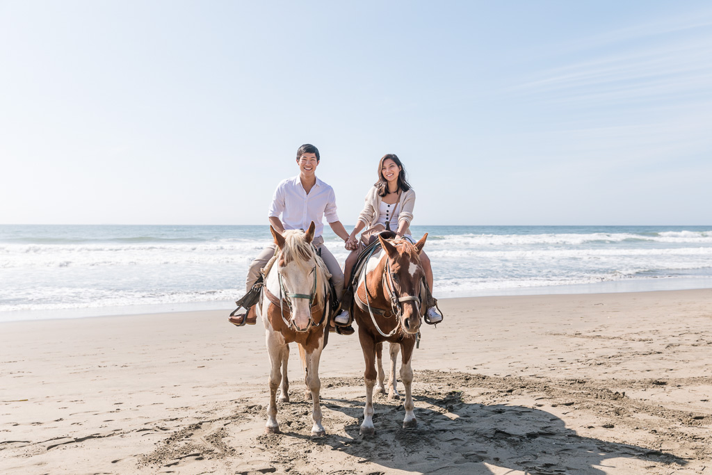 holding hands on horseback ride on the beach