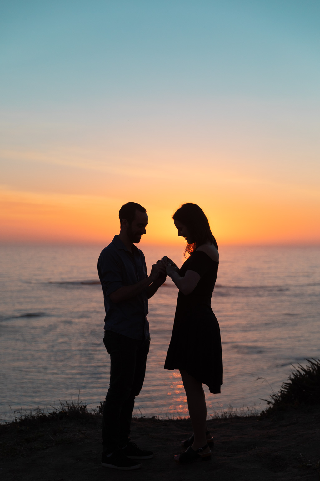 silhouette of couple putting on engagement ring
