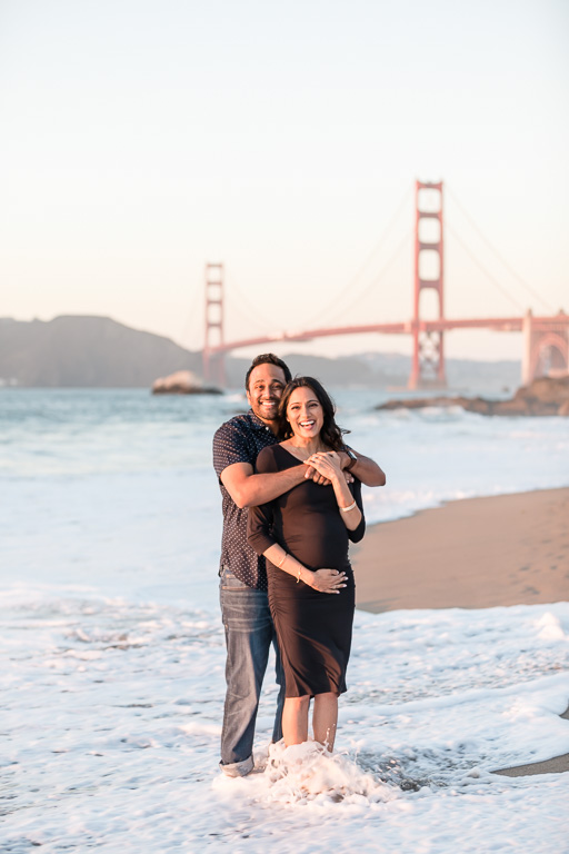 husband and wife maternity photo in ocean waves