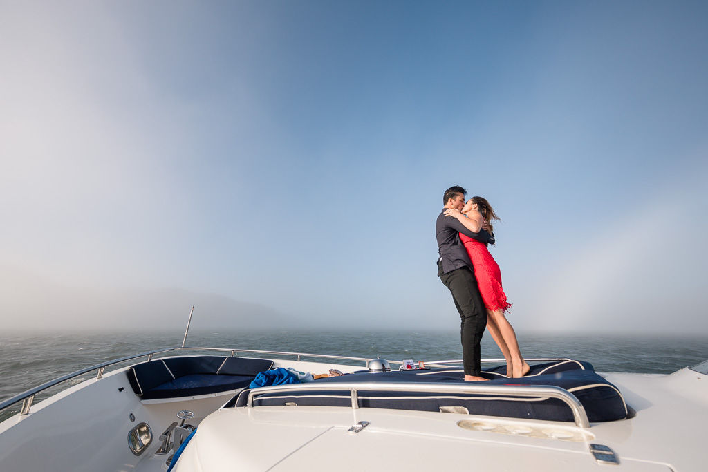 standing and kissing on the bow of a yacht in the San Francisco bay