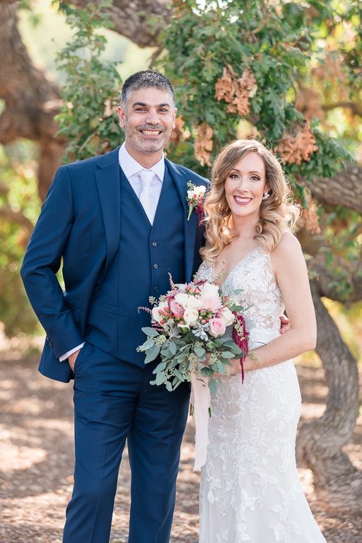 posed portrait of bride and groom in front of giant oak tree at Ruby Hill