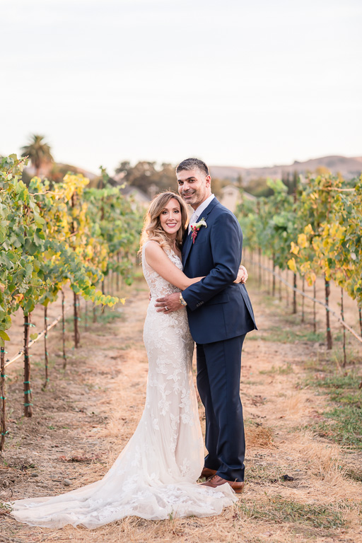 bride and groom in vineyard saying hi to camera