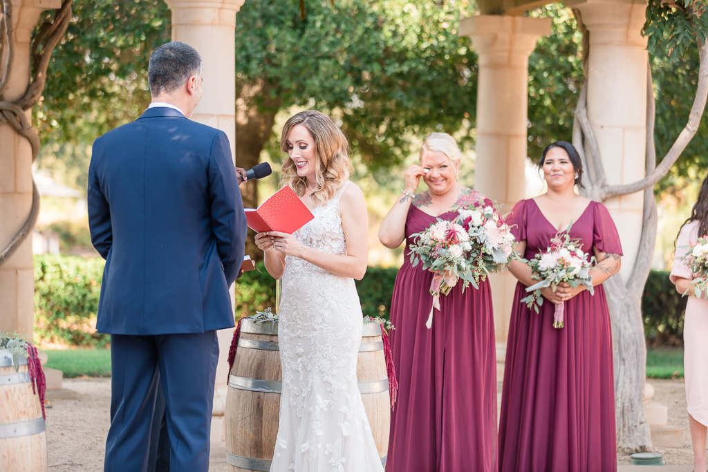 bride reading her vows from her vow book with bridesmaid wiping tears