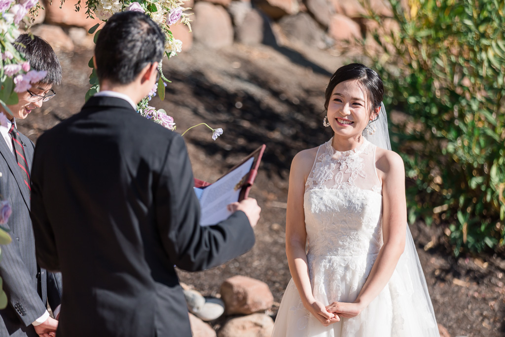 bride smiling at groom reading his marriage vows