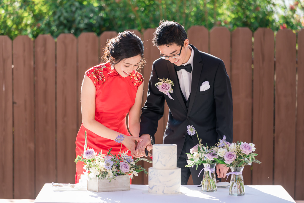 bride and groom cutting cake in traditional qipao dress