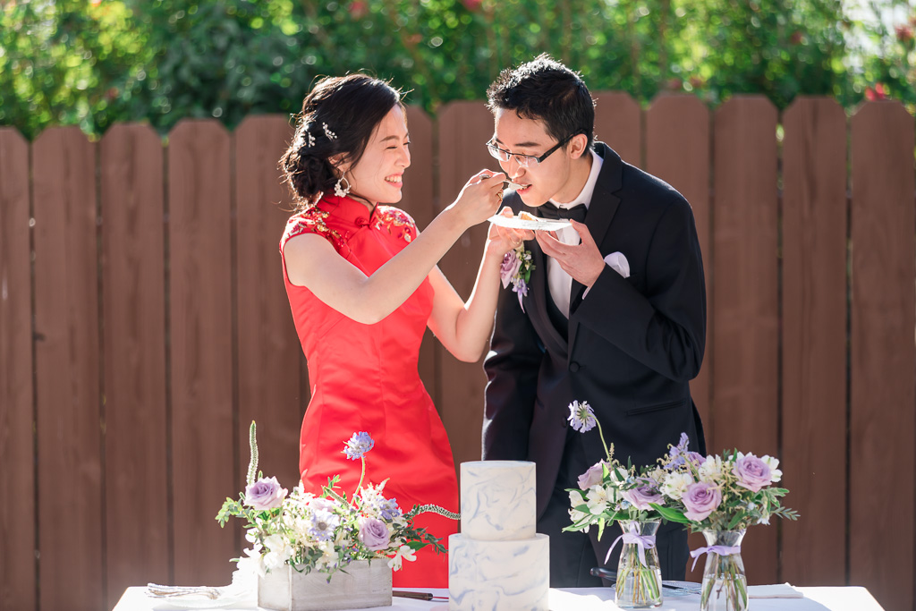 bride laughing and feeding groom cake