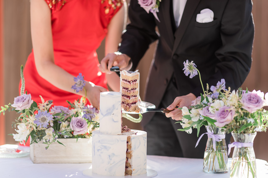 groom cutting out a very professional, neat, nearly equilateral triangle cake slice