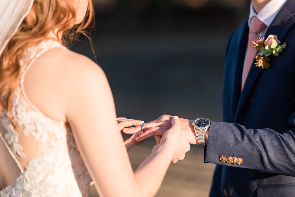 bride slipping wedding ring on groom's finger