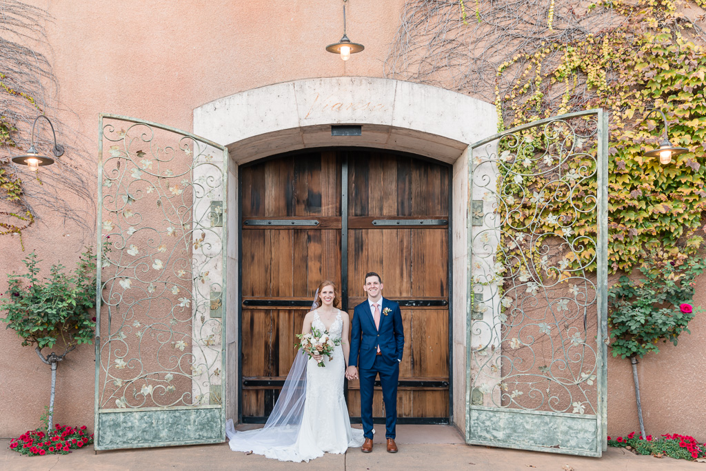 formal wedding photo of bride and groom standing in front of a grand door