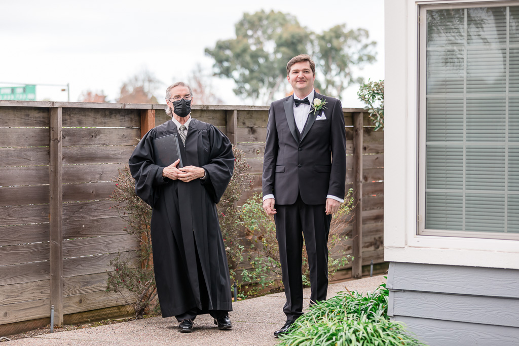 priest and groom entering backyard ceremony