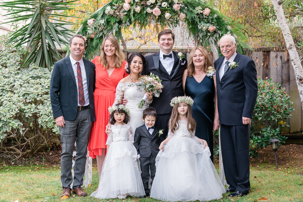 photo of entire family in front of floral wedding arch