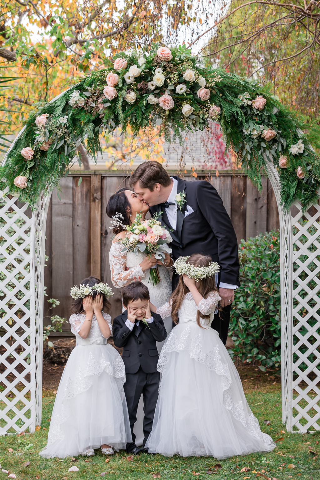 cute family photo with kids in front of wedding arbor arch