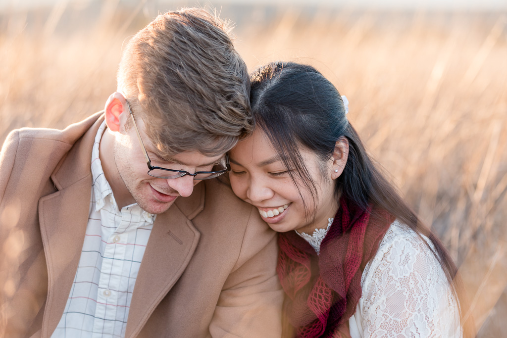 engaged couple snuggling in tall golden grass
