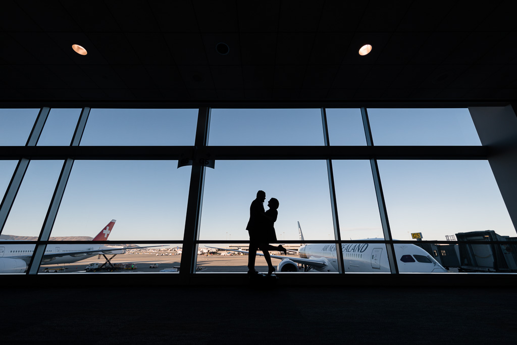 silhouette engagement picture against big window backdrop with airplanes outside