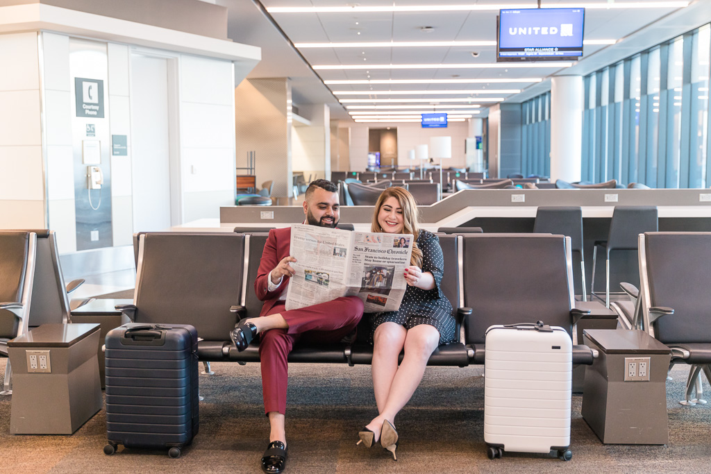 cute engagement photo with newspaper and luggage props