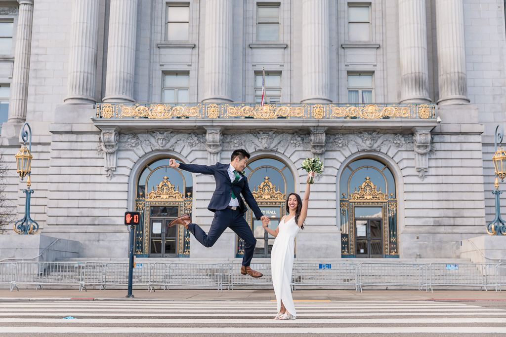 groom jumping for joy in front of San Francisco City Hall
