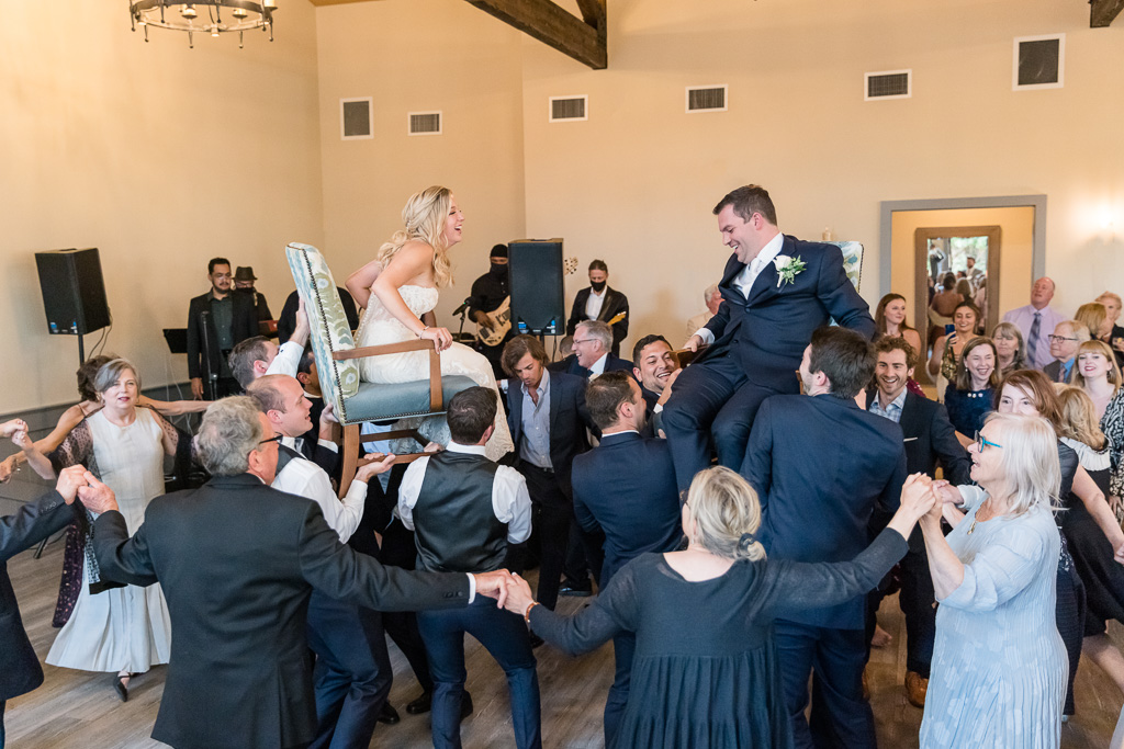 bride and groom lifted up in chairs during wedding reception