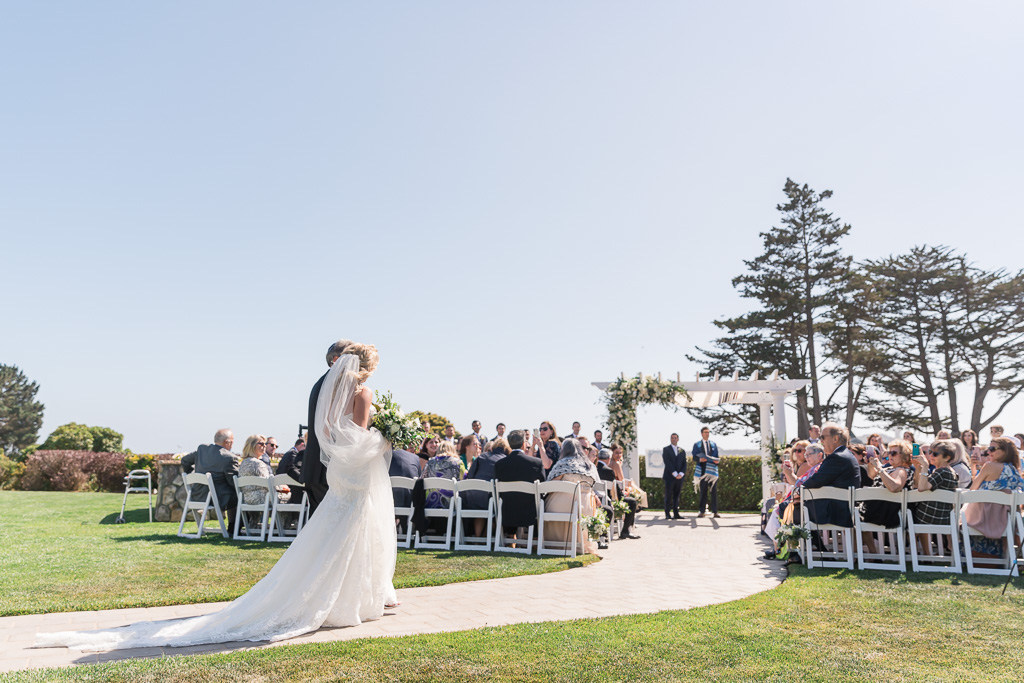 grand photo of bride and father walknig down the aisle at Oceano Hotel, showing bride’s full dress train