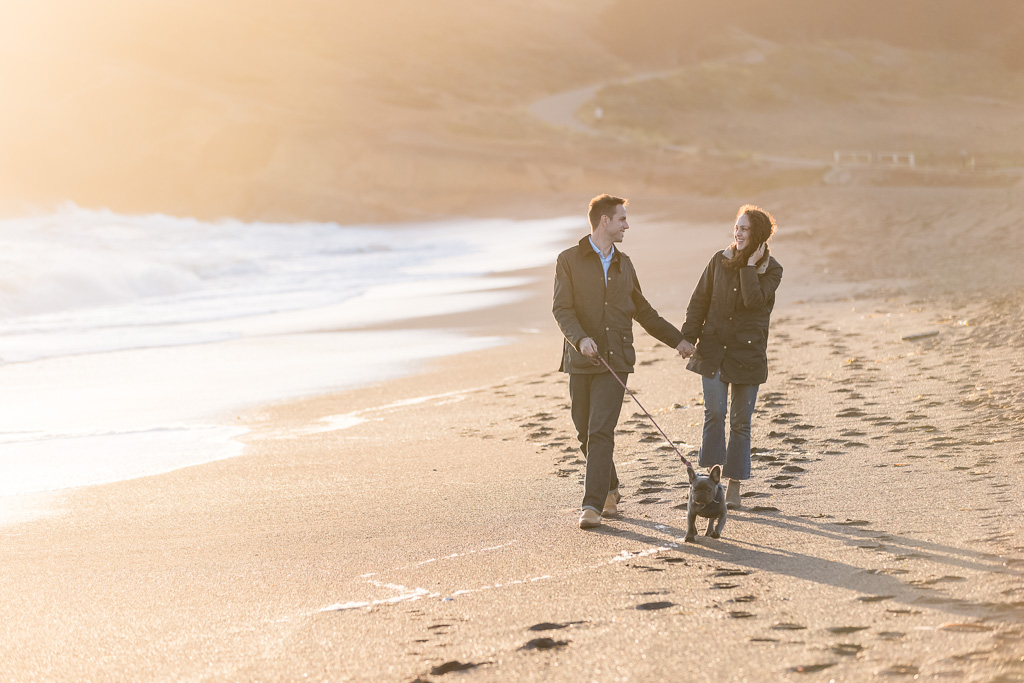 walking along the beach with a puppy for engagement photos
