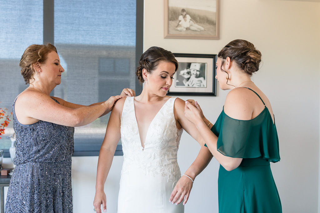 mom and sister helping the bride with her dress