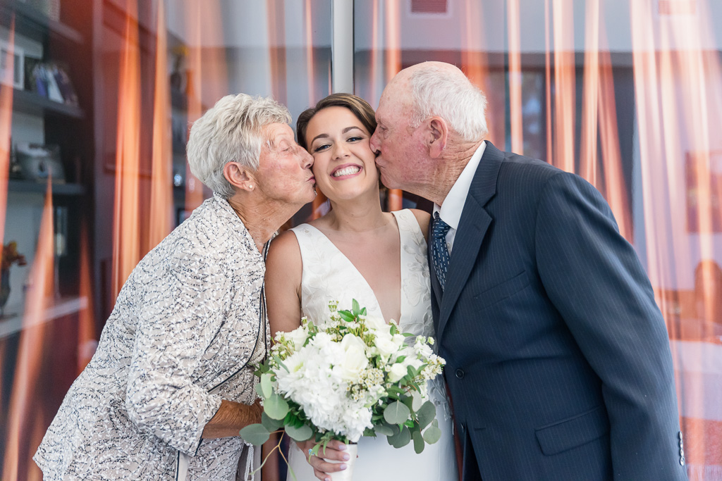 sweet photo of bride and her grandparents kissing her on the cheeks